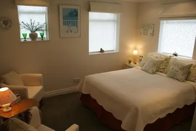 a bedroom with a bed and a chair and two windows at The Norwood Guest House in Southport