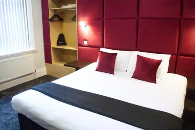 a bedroom with a large bed with a red headboard at The Bromley in Blackpool
