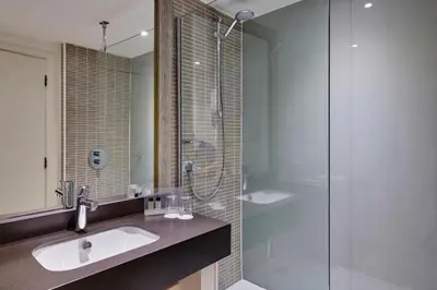 a bathroom with a sink and a glass shower at Holiday Inn Haydock by IHG in Haydock