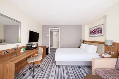 a hotel room with a large bed and a couch at Holiday Inn Haydock by IHG in Haydock