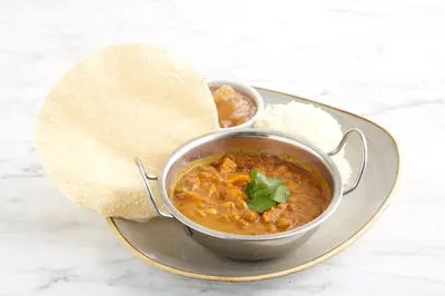 a bowl of curry and rice on a plate at Holiday Inn Haydock by IHG in Haydock