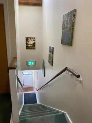a stairway with a green carpet and paintings on the wall at The Farm Burscough in Burscough