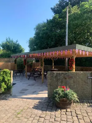 a patio with a pergola and picnic tables and flowers at The Farm Burscough in Burscough