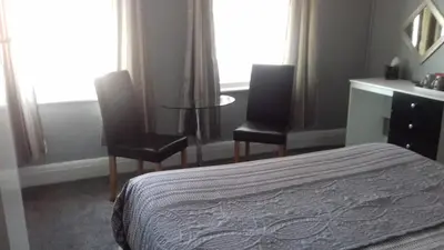 a bedroom with a bed and two chairs and a table at Elmfield in Blackpool