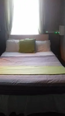 a bed with a green pillow and a window at Elmfield in Blackpool