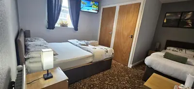 a small bedroom with two beds and a window at Denville Hotel in Blackpool