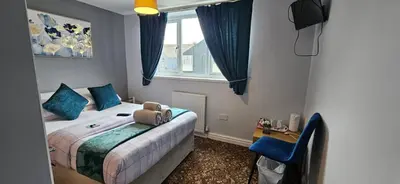 a bedroom with a bed with blue pillows and a window at Denville Hotel in Blackpool