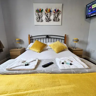 a bed with two towels and two remote controls on it at Denville Hotel in Blackpool