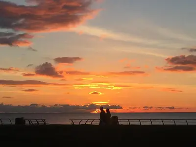 a group of people standing on the beach at sunset at Sandford Promenade in Blackpool
