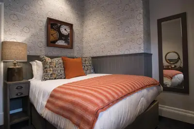 a bedroom with a bed with an orange blanket at Toll House Inn in Lancaster