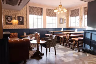 a dining room with tables and chairs and windows at Hartwood Hall by Greene King Inns in Chorley