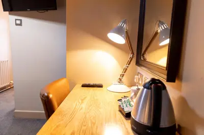 a table with a lamp and a tea kettle on it at Hartwood Hall by Greene King Inns in Chorley