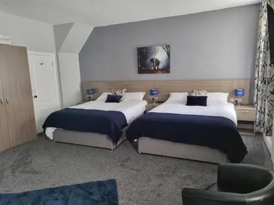 a bedroom with two beds and a chair at Lexham Hotel in Blackpool