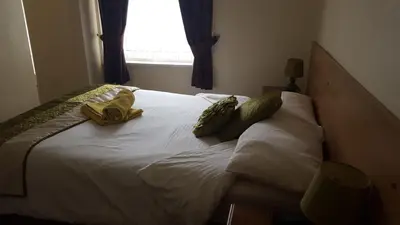 a bed with two towels on it with a window at Lexham Hotel in Blackpool