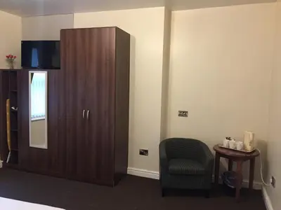 a bedroom with a large wooden cabinet and a chair at Lexham Hotel in Blackpool