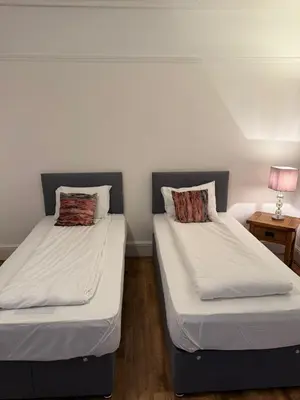 two twin beds in a room with a lamp at Hotel Tia in Liverpool