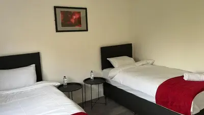 two beds in a room with two tables at Hotel Tia in Liverpool