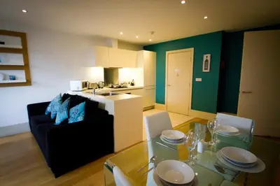 a living room with a dining table and a kitchen at Merchant Quarters Apartments in Liverpool