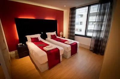 a bedroom with two beds with red walls and a window at Merchant Quarters Apartments in Liverpool