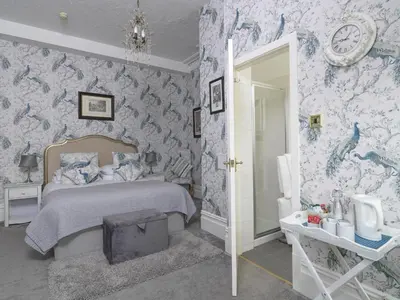 a bedroom with a bed with blue and white wallpaper at Howarth House in Lytham St Annes