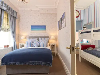 a bedroom with a bed with blue sheets and a window at Howarth House in Lytham St Annes