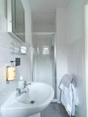 a white bathroom with a sink and a shower at Howarth House in Lytham St Annes