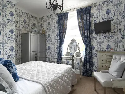 a bedroom with blue and white wallpaper and a bed and a chair at Howarth House in Lytham St Annes