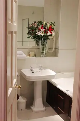 a bathroom with a sink and a vase of flowers at Netherwood Hotel & Spa in Grange Over Sands