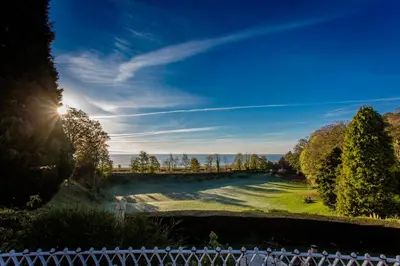 a view of a golf course with the sun in the sky at Netherwood Hotel & Spa in Grange Over Sands