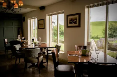 a dining room with tables and chairs and windows at Pyes Mill Hotel Conder Green in Conder Green