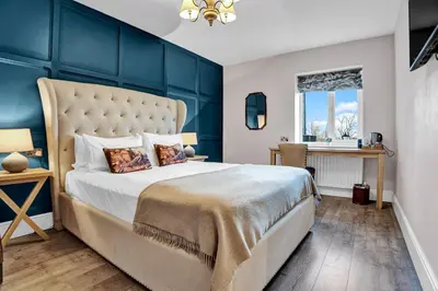 a bedroom with a large bed with a blue wall at Pyes Mill Hotel Conder Green in Conder Green