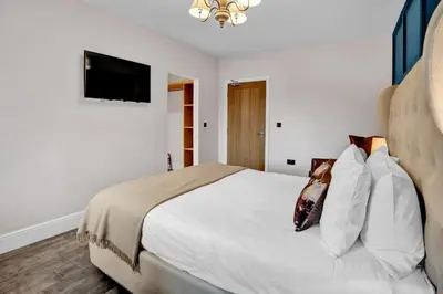 a bedroom with a white bed and a flat screen tv at Pyes Mill Hotel Conder Green in Conder Green