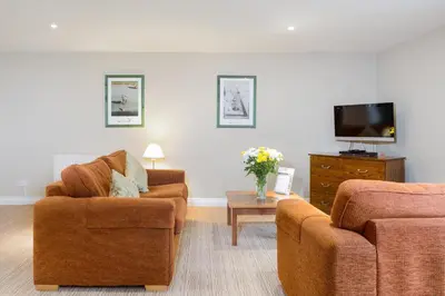 a living room with two chairs and a tv at Thurnham Hall Resort in Cockerham