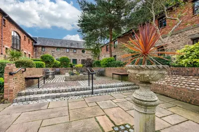 a courtyard with benches and a brick building at Thurnham Hall Resort in Cockerham