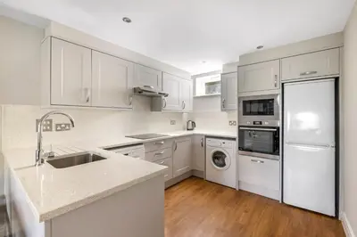 a kitchen with white cabinets and a sink and a dishwasher at Thurnham Hall Resort in Cockerham