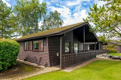 a small wooden house with a yard at Pine Lake Resort in Carnforth
