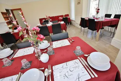 a dining room with a table with red table cloth and chairs at Bayswater House in Blackpool