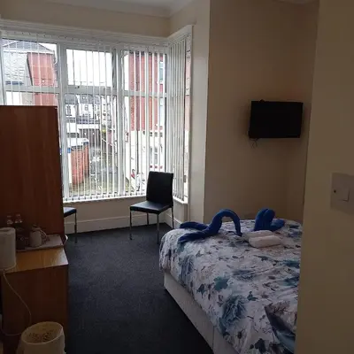 a bedroom with a bed and a chair and a window at Bayswater House in Blackpool