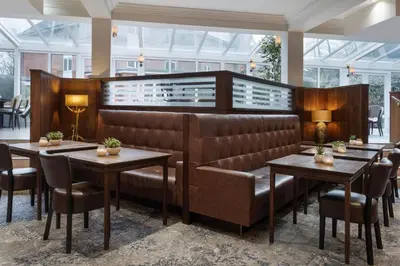 a restaurant with brown leather booths and tables at Delta Hotels by Marriott Preston in Preston