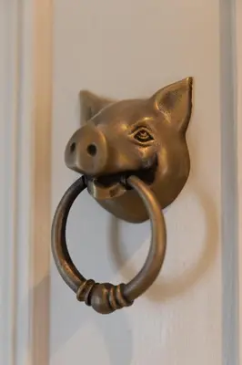 a brass door knocker of a dog with a pipe in its mouth at The Lower Buck Inn in Clitheroe