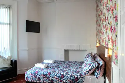 a bedroom with a bed and a tv on the wall at Belroy Hotel in Blackpool