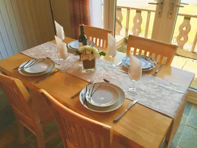 a wooden table with plates and wine glasses on it at Tegid Lodge- Pine Lake Resort in Carnforth