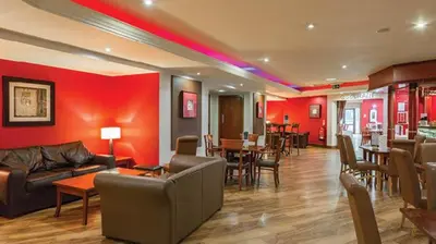 a living room with red walls and a couch and tables at Tegid Lodge- Pine Lake Resort in Carnforth