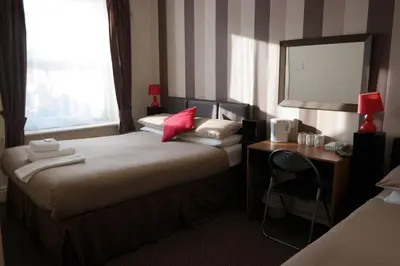 a hotel room with two beds and a desk and a mirror at Boomerang Blackpool in Blackpool