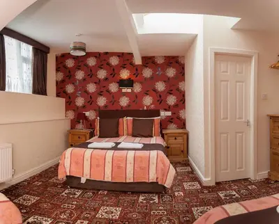 a bedroom with a bed and a red wall at The Trafford Hotel in Blackpool