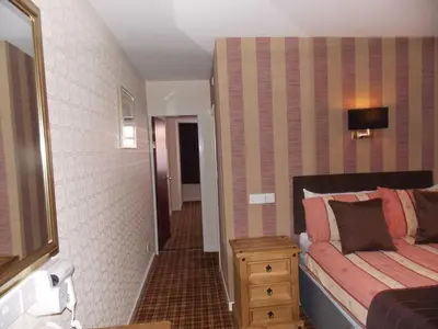 a bedroom with a bed and a dresser and a mirror at The Trafford Hotel in Blackpool