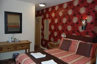 a bedroom with a bed and a red wall at The Trafford Hotel in Blackpool
