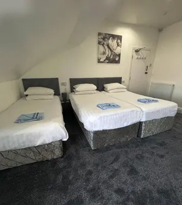 two beds in a hotel room with white sheets at The Mornington Hotel in Blackpool
