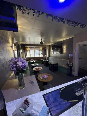 a living room with a couch and tables and flowers at Clifton Private Hotel in Blackpool
