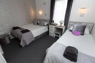 a bedroom with two beds and a desk with a window at The Carlton in Blackpool